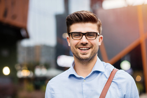 portrait of young entrepreneur. handsome smart casual man with eyeglasses and blue shirt smiling to camera - Foto, imagen