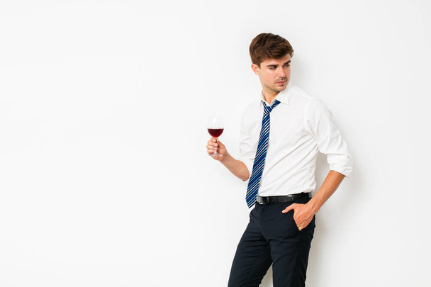wine of winners. Elegant man having a glass of wine after a long office day, relaxing his mind, on white background - Zdjęcie, obraz