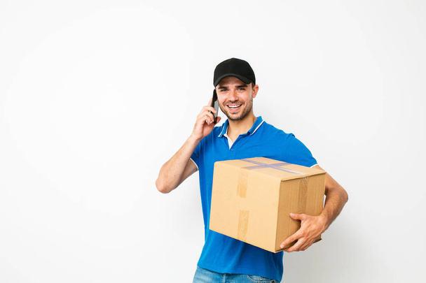 fast delivery. happy delivery man talking at mobile phone with the client who need to deliver his package, isolated on white - Valokuva, kuva