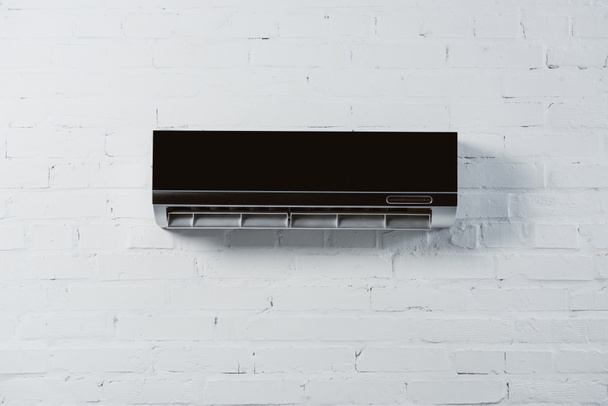 ar condicionado moderno pendurado na parede de tijolo branco
 - Foto, Imagem