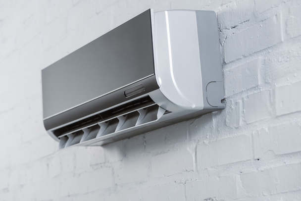 lähikuva laukaus modernin ilmastointilaitteen roikkuu valkoinen tiili seinään
 - Valokuva, kuva