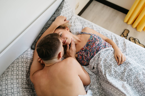 high angle view of young adult couple hugging on bed - Фото, изображение