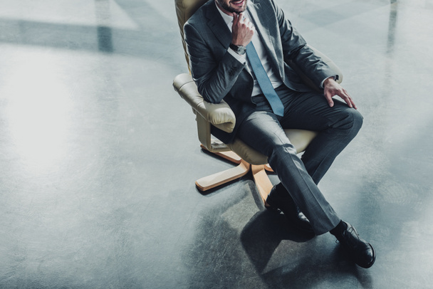 plan recadré d'un bel homme d'affaires assis sur un fauteuil de luxe au bureau moderne
 - Photo, image
