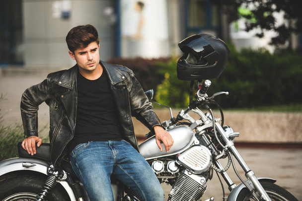 young and cool. handsome and relaxing man sitting on his motorcycle, in a city center waiting for someone - Foto, Bild