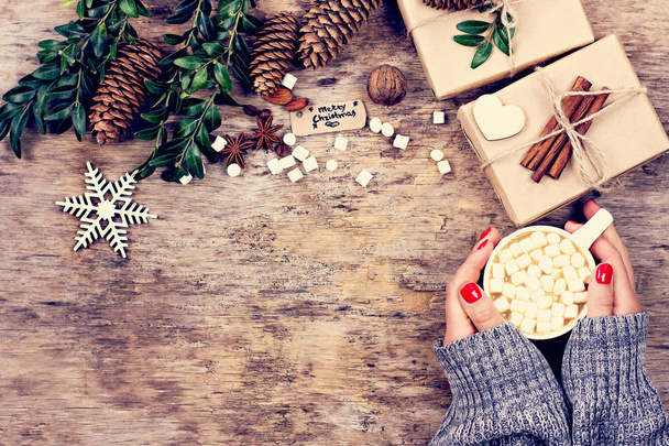 Κακάο, καφές, δώρο, έλατο, καρύδια, κώνους, ζεστή πλεκτή κουβέρτα. Χριστουγεννιάτικα μπισκότα Το χέρι μιας γυναίκας κρατά ένα φλιτζάνι. Χειμώνας, Πρωτοχρονιά, Χριστούγεννα νεκρή φύση.  - Φωτογραφία, εικόνα