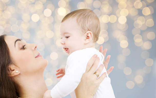 mother with baby over festive lights background - Фото, изображение