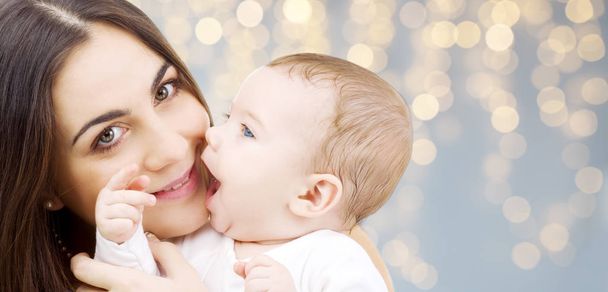 mother with baby over festive lights background - Photo, Image