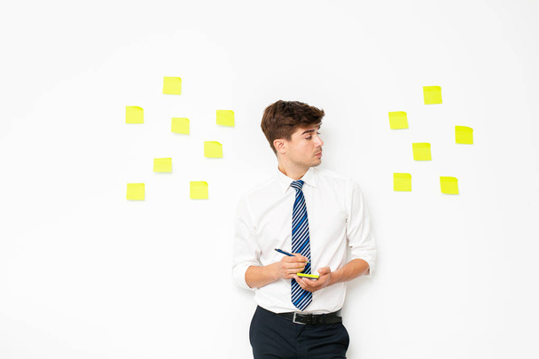 office guy at work, writing on post it on white wall, reminder notes, plans and  objectives - Foto, Imagem