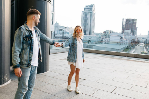 scenic view of smiling young adult couple against modern cityscape  - Foto, afbeelding