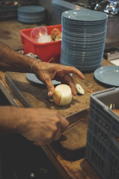 Male hands peeling and cutting onion on wooden chalkboard - Fotoğraf, Görsel