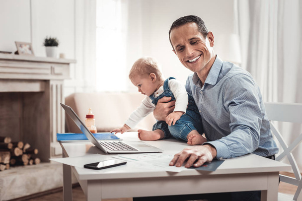 Happy positive businessman holding his child - Foto, afbeelding