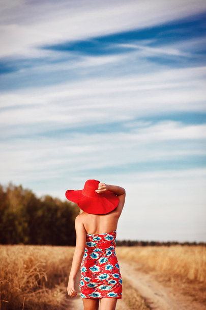 alan üzerinde kırmızı şapka ile Kırmızı elbiseli kız - Fotoğraf, Görsel