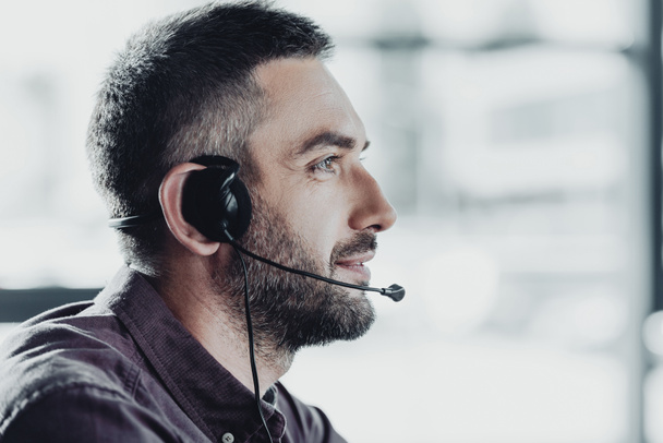 side view of handsome call center worker in headphones with microphone - Fotó, kép