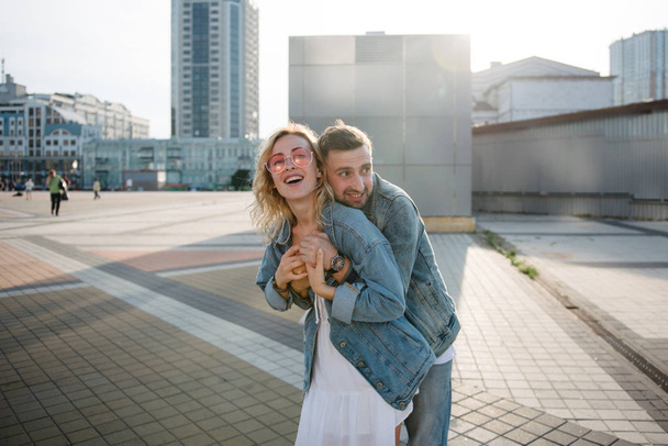 scenic view of hugging young adult couple against modern cityscape  - Foto, Imagem