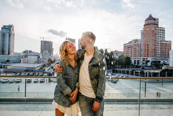 scenic view of smiling young adult couple against modern cityscape  - Фото, изображение