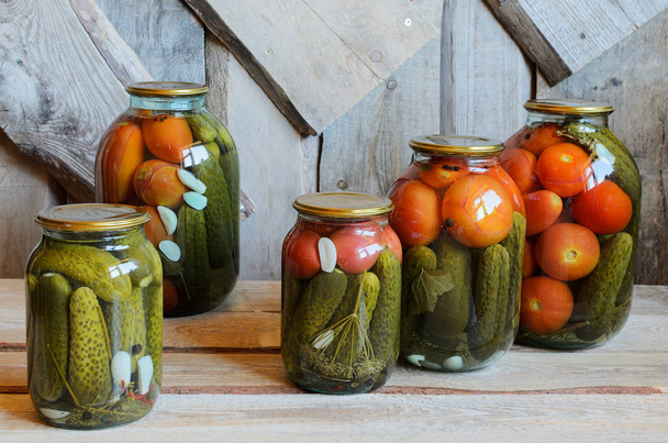 Glazen potten met Ingeblikte tomaten en komkommers. Houten achtergrond - Foto, afbeelding