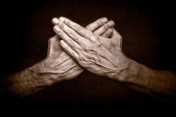 Φωτογραφία του ανθρώπου σταυρωμένα χέρια σε σκούρο φόντο, που συμβολίζει την προστασία της ασφάλειας - Φωτογραφία, εικόνα