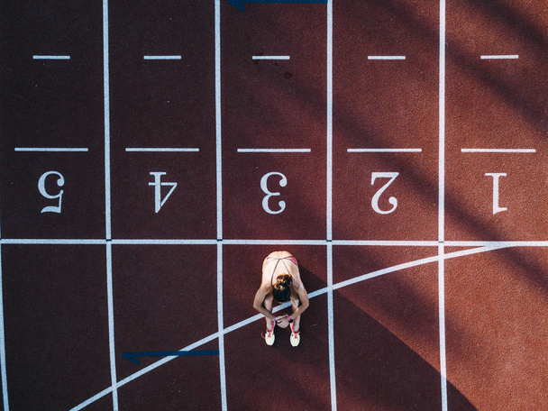 Visione aerea una atleta donna seduta in pista
 - Foto, immagini