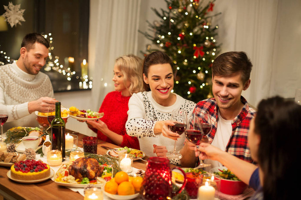 happy friends drinking red wine at christmas party - Фото, изображение