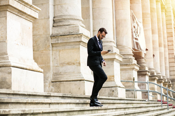busy elegant stylish man, successful businessman, walking on stairs of important building, university or law court going to an important meeting - Фото, зображення