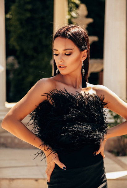 fashion outdoor photo of sexy beautiful woman with dark hair in luxurious black cocktail dress posing in villa - Photo, Image