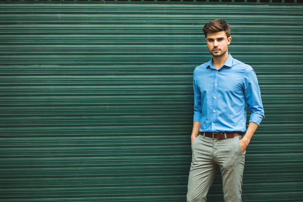 confidence and elegance. young man in smart casual outfit for office day looking confident on a green background with empty space for text - Foto, afbeelding