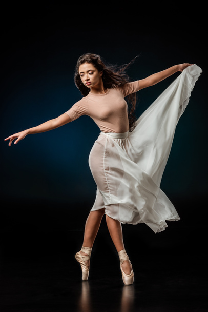elegant female ballet dancer in white skirt dancing on dark background - Fotó, kép