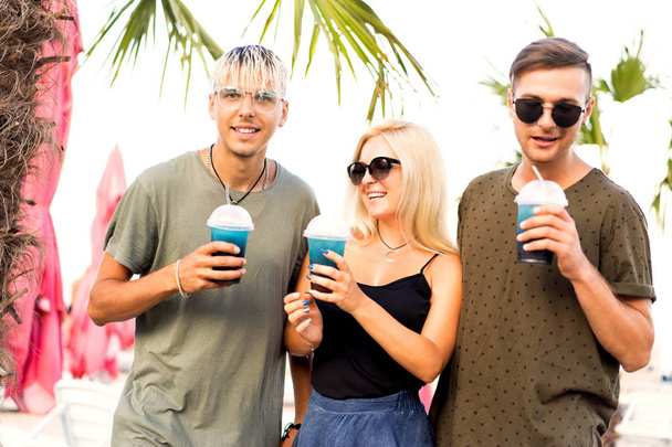 three friends cheerful company rest on a tropical beach and drink cocktails, very, magazine concept - 写真・画像