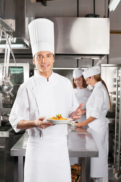 Confident Chef Presenting Dish In Commercial Kitchen - Фото, изображение