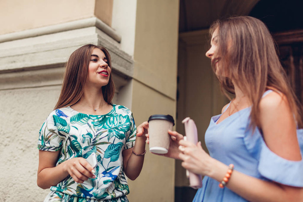 Two young beautiful women talking drinking coffee. Girls having fun in city. Best friends chat outdoors. College teens - Fotoğraf, Görsel
