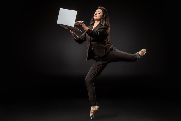 mulher de negócios em terno e sapatos de balé usando laptop no fundo preto
 - Foto, Imagem