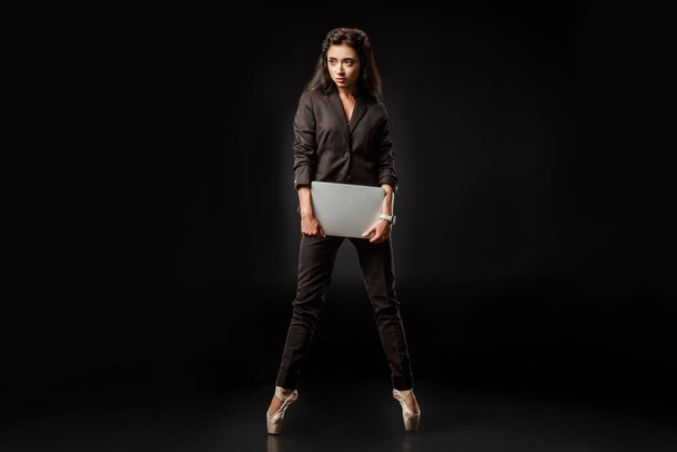 beautiful businesswoman in suit and ballet shoes with laptop on black background - Foto, Bild