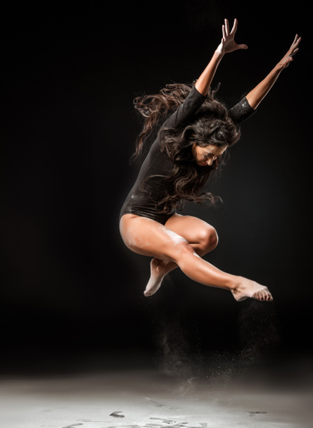 schöne Ballerina im schwarzen Body springt auf dunklem Hintergrund - Foto, Bild