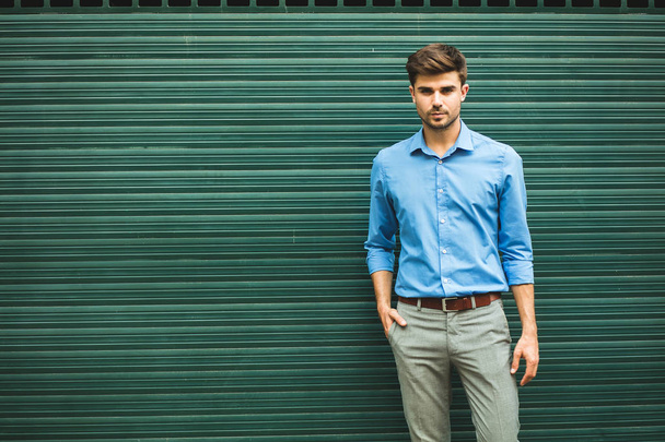 confidence and elegance. young man in smart casual outfit for office day looking confident on a green background with empty space for text - Photo, image