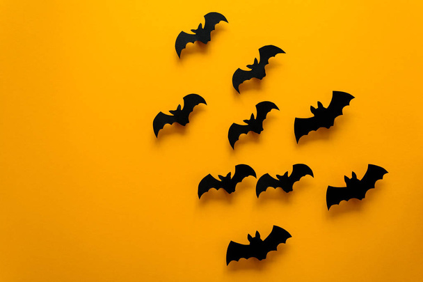 Black paper bats flying on yellow background. Halloween concept. Paper cut style. Top view - Foto, Imagem