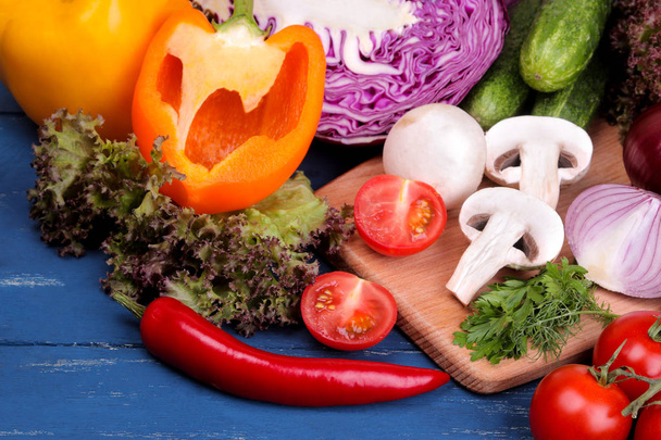 Verduras frescas incluyendo ajo pepino col cebolla pimienta remolacha zanahoria calabacín y tomates en una mesa de madera azul
 - Foto, imagen