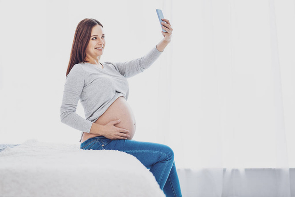 Charming pregnant woman being busy with making selfies - Фото, зображення