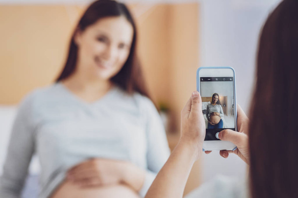 Pregnant woman being photographed by her daughter - Photo, image