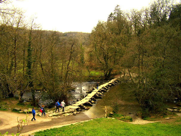 Een groep van toeristen wandelen in Exmoor National Park Somerset Engeland, voor te bereiden op de oude Tarr Steps Bridge oversteken. - Foto, afbeelding