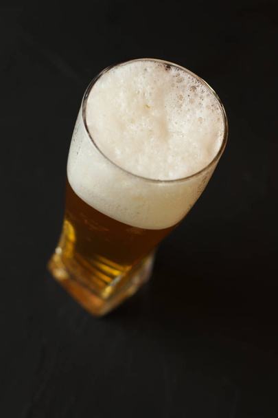 Light beer in a glass bowl on a black background. Beer in the bar. - Фото, изображение
