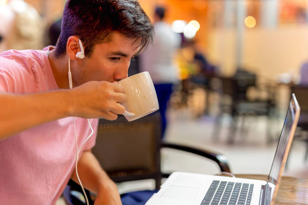 Μικτή φυλή studen πίνοντας καφέ ενώ εργάζονται σε υπολογιστή ΕΤΕΣΑ - Φωτογραφία, εικόνα