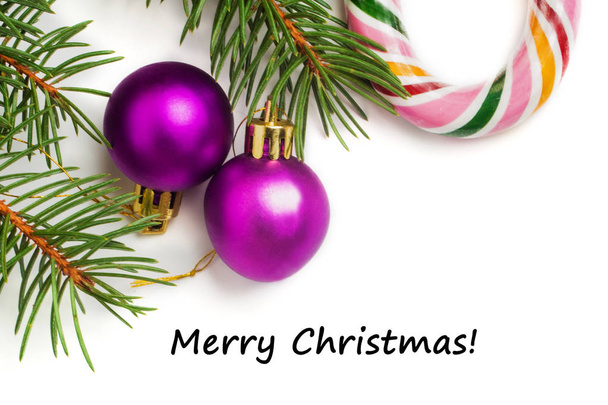 Decoração festiva de Natal e Ano Novo, duas bolas roxas, doces coloridos e abeto isolado no fundo branco. Vista de cima. Texto Feliz Natal
 - Foto, Imagem