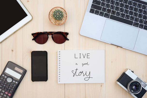 Live a good story. Inspirational quote with flat lay of accessories on wooden desk background. - 写真・画像