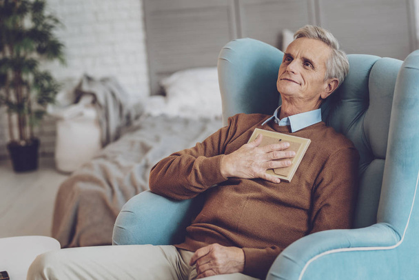Delighted gray-haired man having rest at home - Фото, изображение