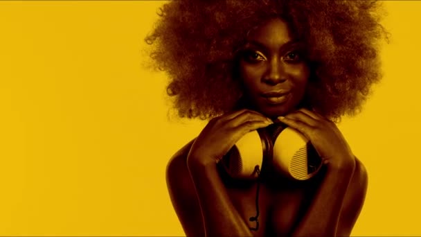 schöne Afrikanerin mit großer Afro-Perücke und Kopfhörer - Filmmaterial, Video