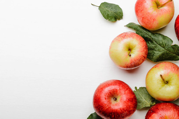 Manzanas maduras rojas y amarillas con hojas verdes sobre fondo blanco. Buena cosecha. Copiar espacio
 - Foto, Imagen
