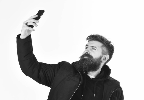 Man with calm face in warm clothes and holds phone - Foto, Imagem