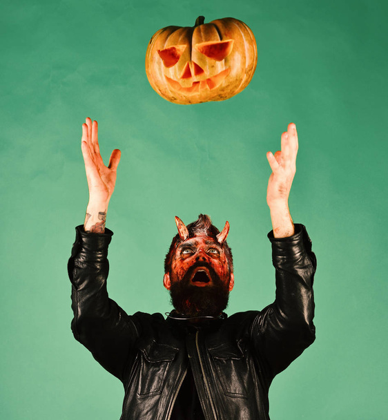 Halloween party concept. Man wearing scary makeup throws pumpkin up - Fotografie, Obrázek