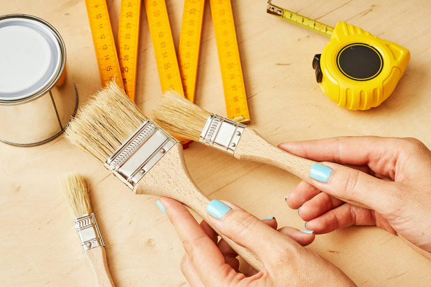 mujer sosteniendo pinceles para pintar en sus manos sobre la mesa con herramientas
 - Foto, imagen