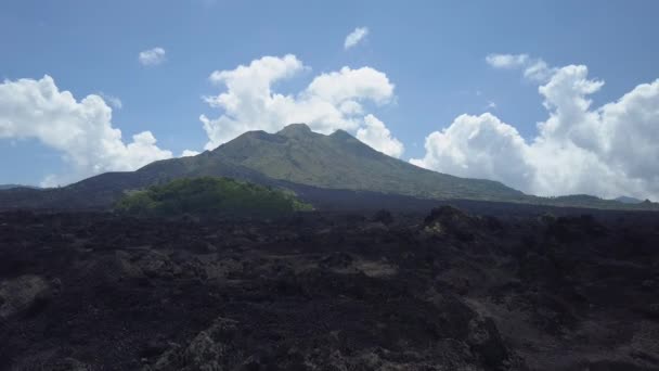 Luchtfoto Close Up vliegen boven ruwe steenachtige zwarte lava terrein en grijze gewone vulkanische bodem bij de toeten van de bergketen van de Gunung Batur in Bali, Indonesië. Dramatische landschap op Kintamani vulkaan krater - Video